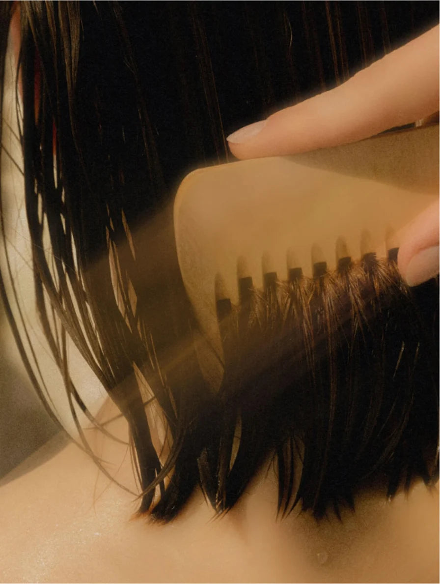 Close-up of a hairbrush with bristles and a handle, held by a hand.