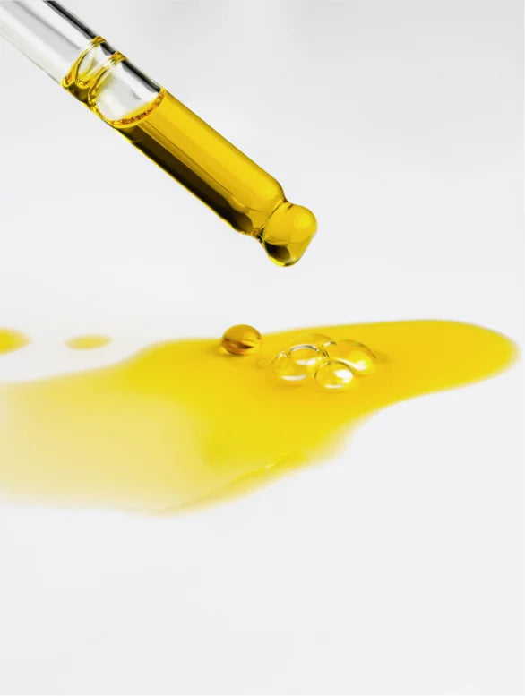 Close-up on a serum dropper with yellow oil.