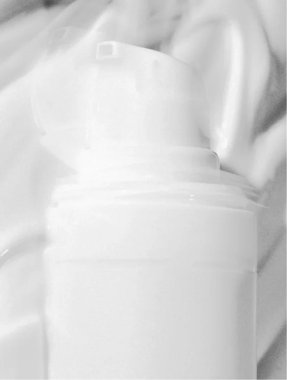 Moisturising cream airless tube pump close-up on a white cream texture background.