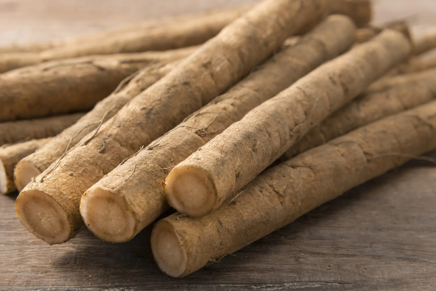 Stack of burdock roots on a wooden surface.