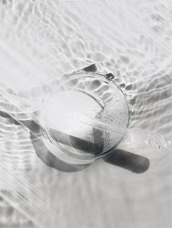 Glass with dropper on a water reflection background.