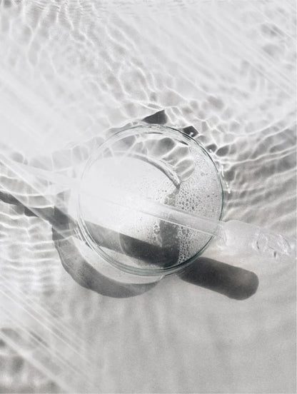 Glass with dropper on a water reflection background.