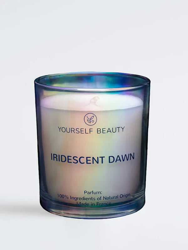 Candle in a glass jar labeled 'Iridescent Dawn' by 'Yourself Beauty' on a white background.