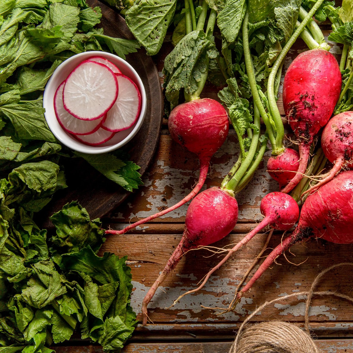 Fresh radishes with green leaves on a wooden surface.