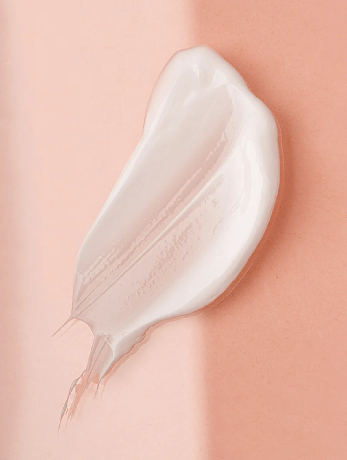 White serum swatch on a pink background.